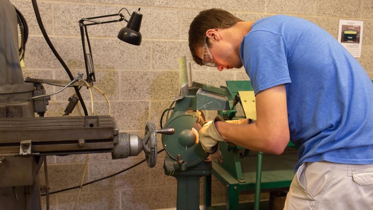 Student working in machine shop creating an object
