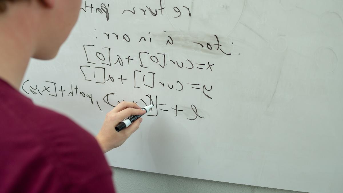 person writing equations on a white board