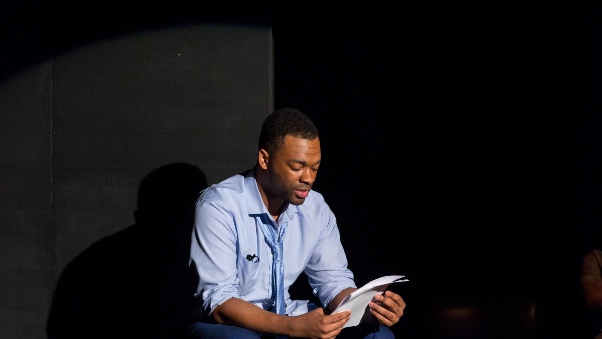 black man sitting in a chair and reading a book